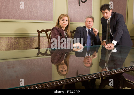 Portrait of three multi-racial businesspeople sitting in boardroom Stock Photo