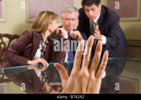 Hand raised, three executives meeting in background Stock Photo