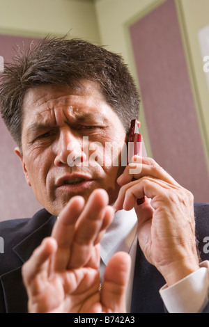 Middle-aged businessman using mobile phone, gesturing Stock Photo