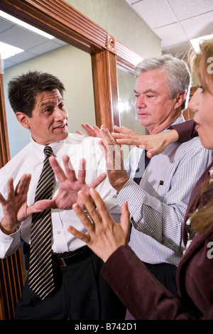 Three multi-ethnic businesspeople having discussion in office corridor Stock Photo