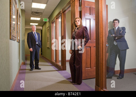 Portrait of three business executives standing in office corridor Stock Photo