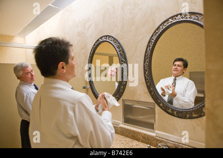 Two multi-racial businessmen standing in office bathroom Stock Photo