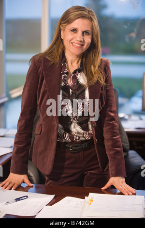 Portrait of middle-aged female office worker standing at desk in office Stock Photo