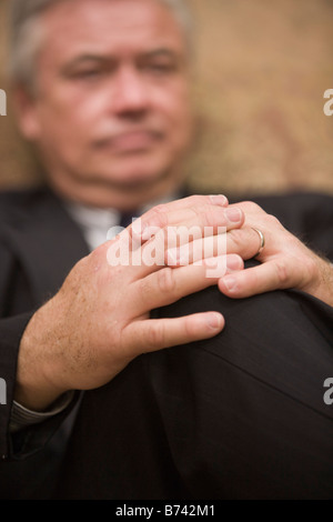 Mature businessman in deep thought, focus on hands Stock Photo