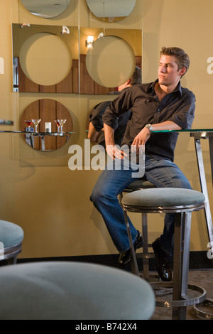 Handsome young man sitting on bar stool in restaurant Stock Photo