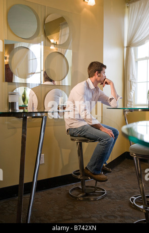 Handsome young man sitting on bar stool in restaurant Stock Photo