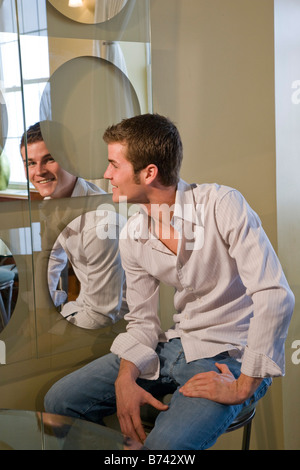 Young man looking at reflection in mirror Stock Photo