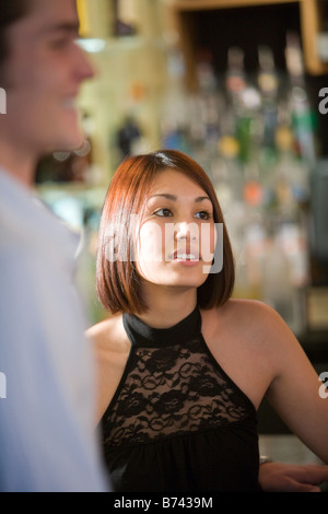 Young woman wearing a black halter top sitting at bar Stock Photo
