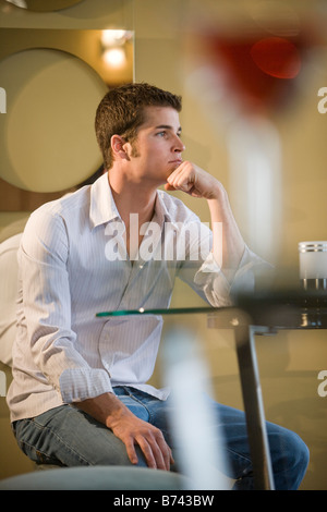Young man sitting at a table inside a restaurant Stock Photo