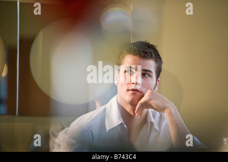 Young man with hand resting on chin Stock Photo