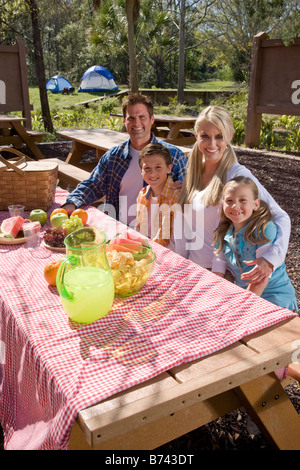 Young happy family sitting at picnic table near campsite Stock Photo