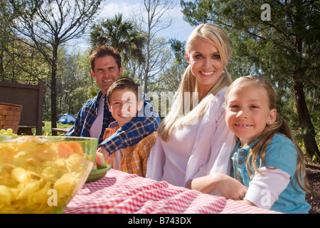 Young happy family sitting at picnic table near campsite Stock Photo