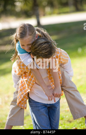 Boy giving piggyback ride to girl in park