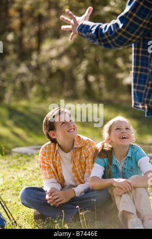 Children playing in park looking up at dad Stock Photo