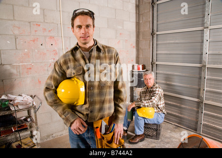 Men holding hardhats taking break at construction site Stock Photo
