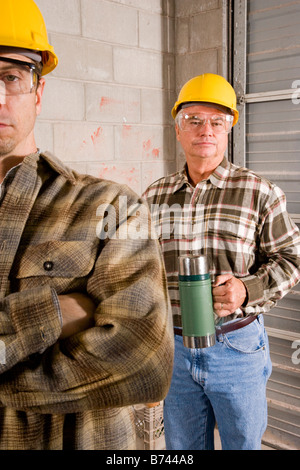 Men wearing hardhats holding thermos at construction site Stock Photo