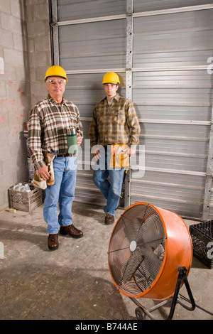 Men wearing hardhats holding thermos at construction site Stock Photo