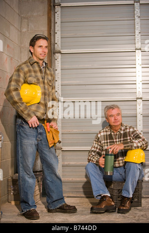 Male workers with hard hats taking coffee break Stock Photo