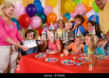 Group of children having fun at birthday party, mother holding cake Stock Photo
