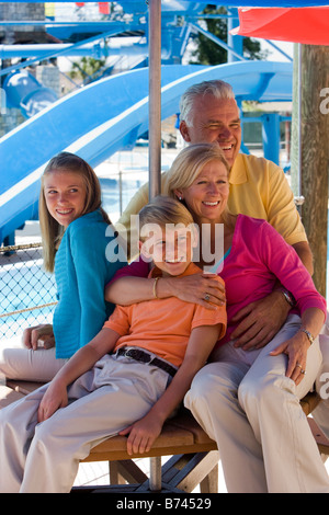 Portrait of family sitting together under shady umbrella at water park Stock Photo