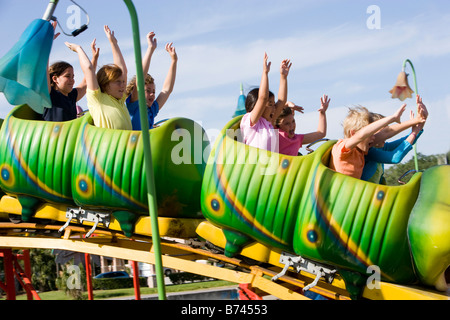 Children riding a rollercoaster at amusement park Stock Photo
