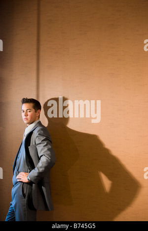 Young businessman in suit leaning against wall Stock Photo
