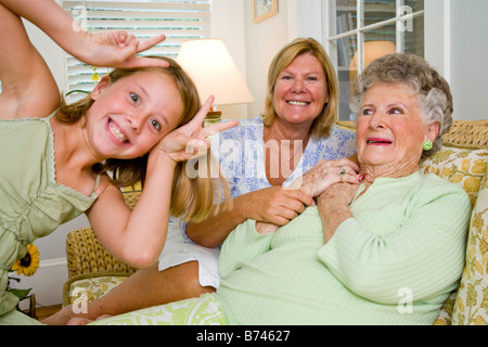 Girl having fun next to grandmother and great grandmother in living room Stock Photo