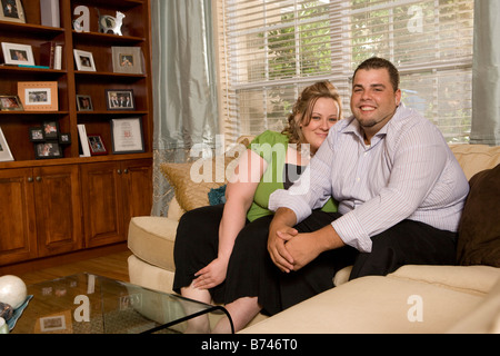 Overweight couple sitting on sofa in living room Stock Photo