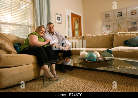 Overweight couple sitting on sofa in living room Stock Photo
