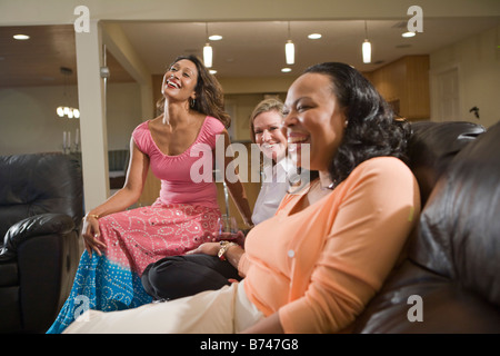 Three happy multi-ethnic women sitting in modern living room Stock Photo