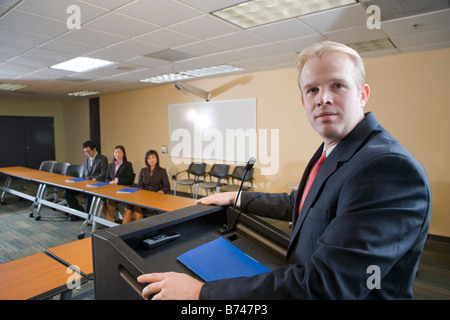 Businessman giving speech in front of Asian business people in boardroom Stock Photo
