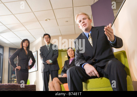 Caucasian businessman waiting in lobby with three Asian executives Stock Photo