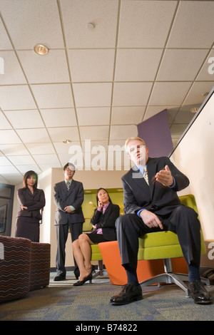 Caucasian businessman waiting in lobby with three Asian executives Stock Photo