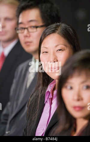 Businesspeople sitting in a row, focus on young Asian woman Stock Photo