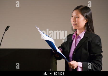 Young Asian businesswoman with presentation next to podium Stock Photo