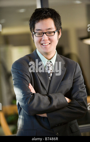 Young Asian businessman standing with arms crossed in boardroom, smiling Stock Photo