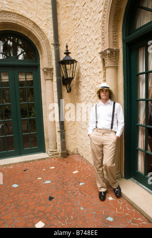 Stylish young man wearing hat leaning against outside of building Stock Photo