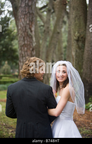 Young bride and groom standing arm in arm outside on wedding day, rear view Stock Photo