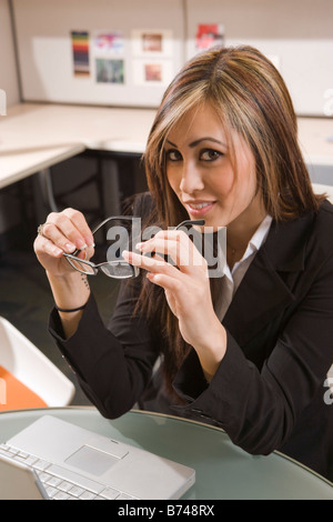 Young female office worker sitting at desk with laptop Stock Photo