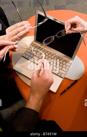 High angle view of hands holding eyeglasses over laptop Stock Photo