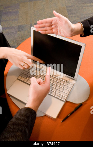 Three hands pointing to laptop screen Stock Photo
