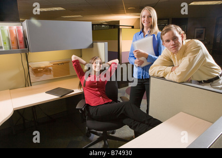 Three young multi-ethnic office workers hanging out at cubicle desk Stock Photo
