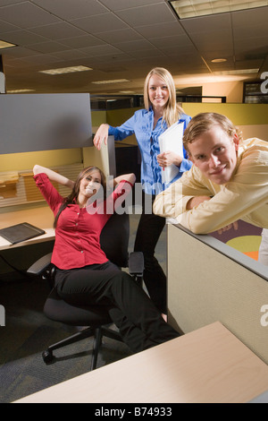 Three young multi-ethnic office workers hanging out at cubicle desk Stock Photo