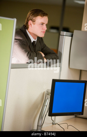 Young male office worker leaning on cubicle wall Stock Photo