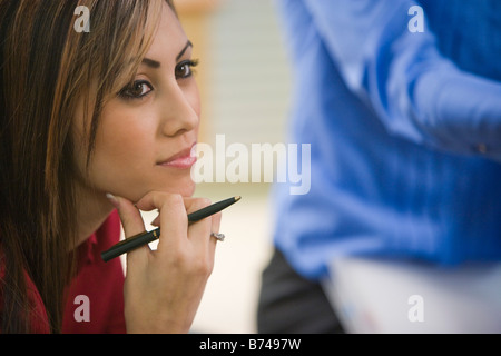 Pretty face of young office worker holding pen and listening Stock Photo