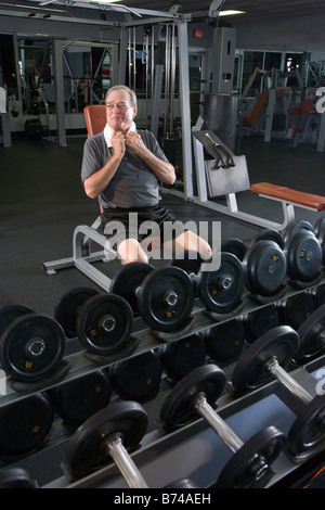 Portrait of senior man working out at gym, seating on bench Stock Photo