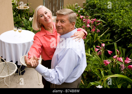 Side view of senior couple dancing in garden patio Stock Photo