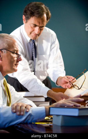 Businesspeople discussing in office holding glasses with books on table Stock Photo