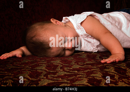 Baby girl lying on sofa crying Stock Photo