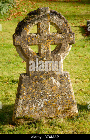 Ancient grave stone, in a churchyard, with cross enclosed in a circle and lichen growing on it. Stock Photo